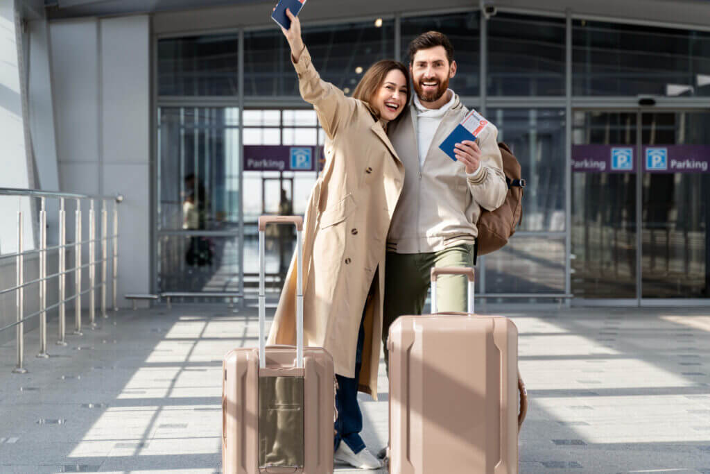 couple heureux avec des valises devant un aéroport