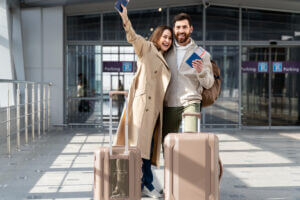 couple heureux avec des valises devant un aéroport